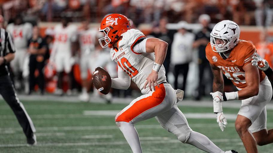 Quarterback Grant Gunnell keeps the ball while defended by Texas Longhorns defensive linemen Lance Jackson.