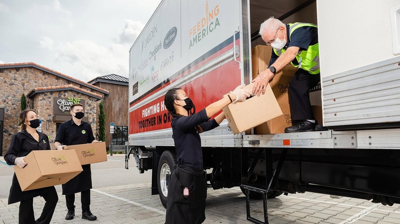 Olive Garden workers carry boxes of food to a Feeding America donation truck.