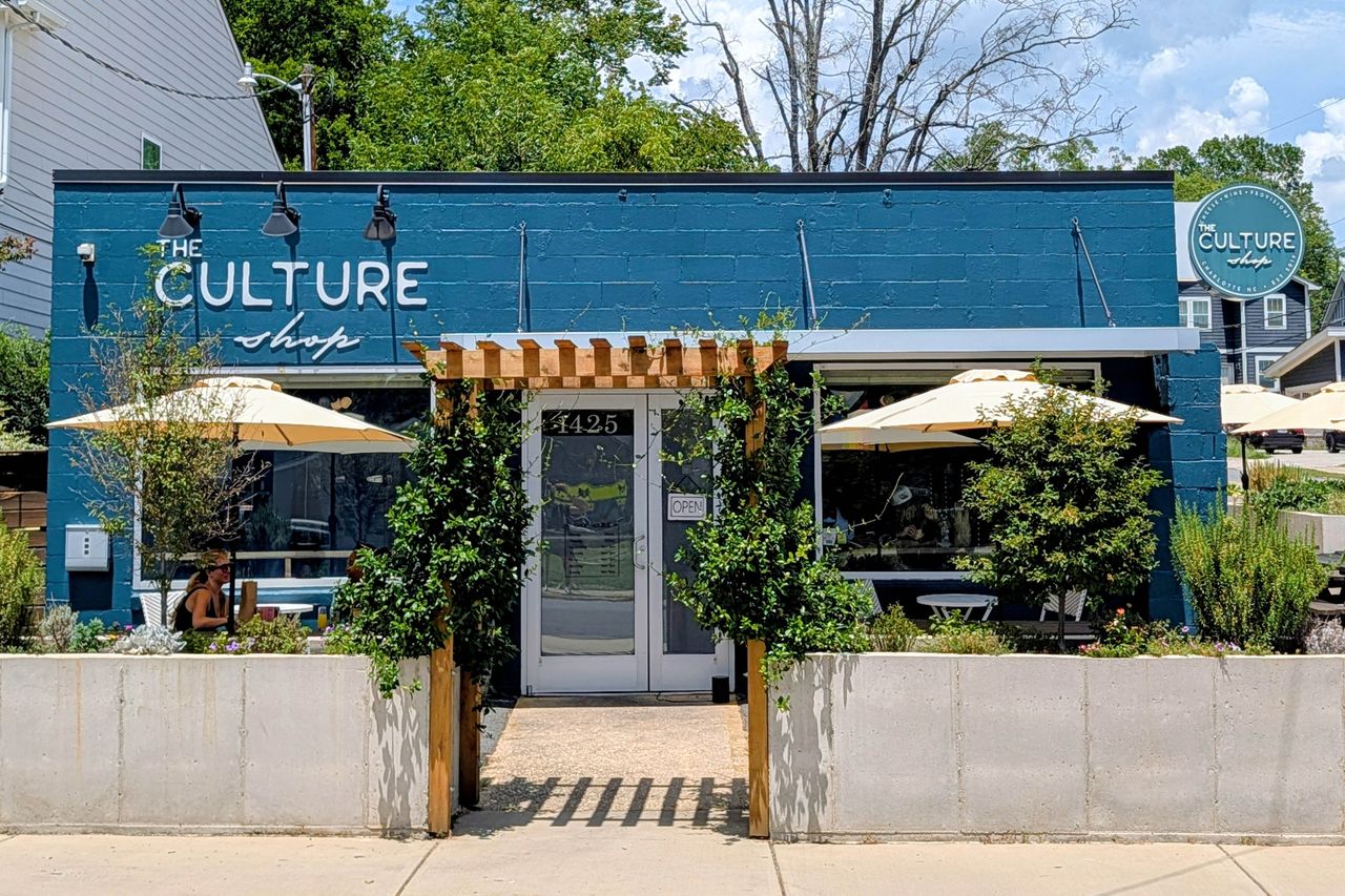 Facade of The Culture Shop showing a small storefront with outdoor seating and greenery