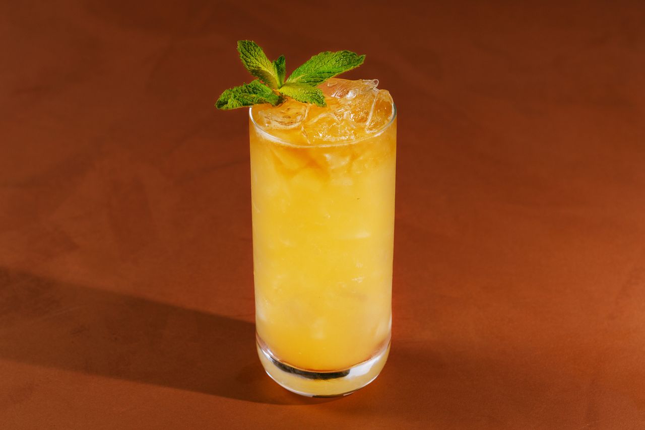 A Fog Cutter cocktail on a rust colored surface.