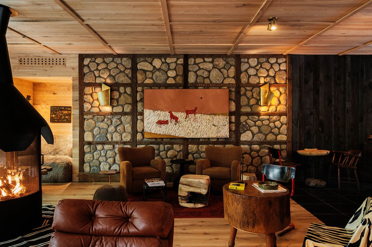 Cozy lounge area with a stone wall central artwork various seating arrangements and a fireplace