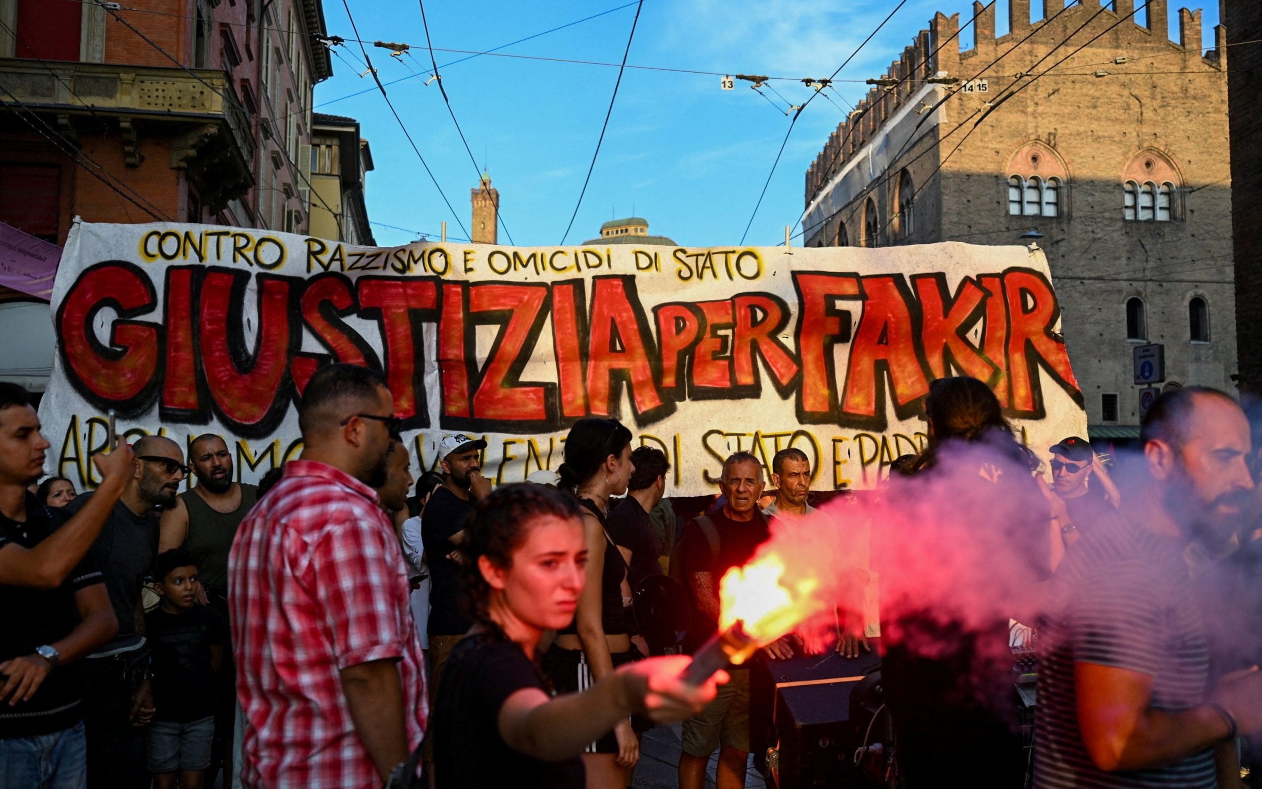 A protester holds a flare in front of a banner reading in Italian