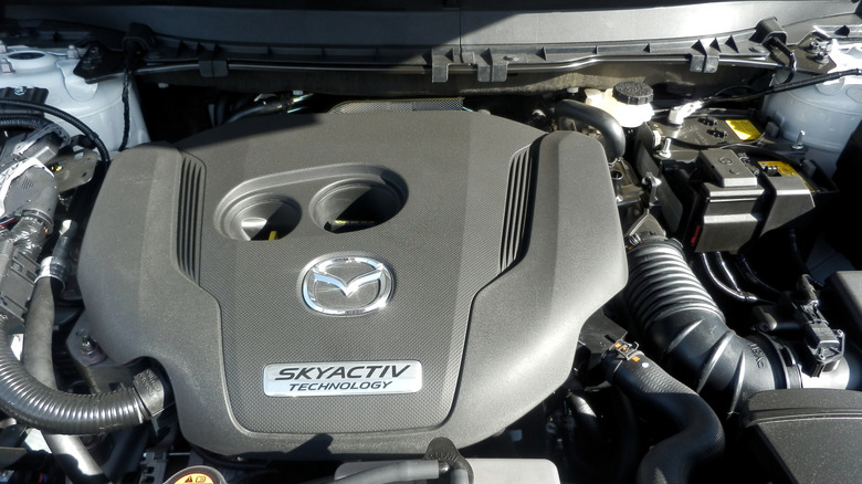 The engine bay of a white Mazda CX-9 SUV showing the engine with "Skyactiv" clearly lettered across the cover.