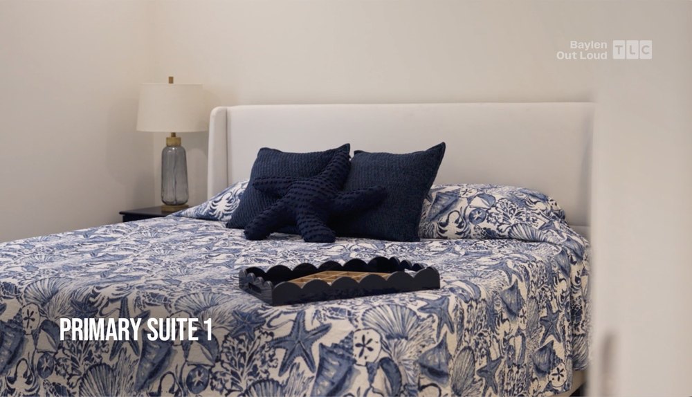 The primary bedroom features a king-sized bed covered in a blue seashell-patterned comforter.