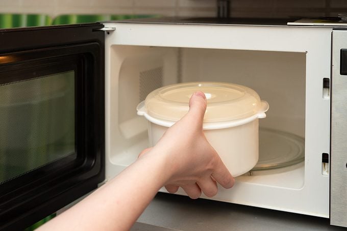 Putting Food Container Into Microwave Oven.