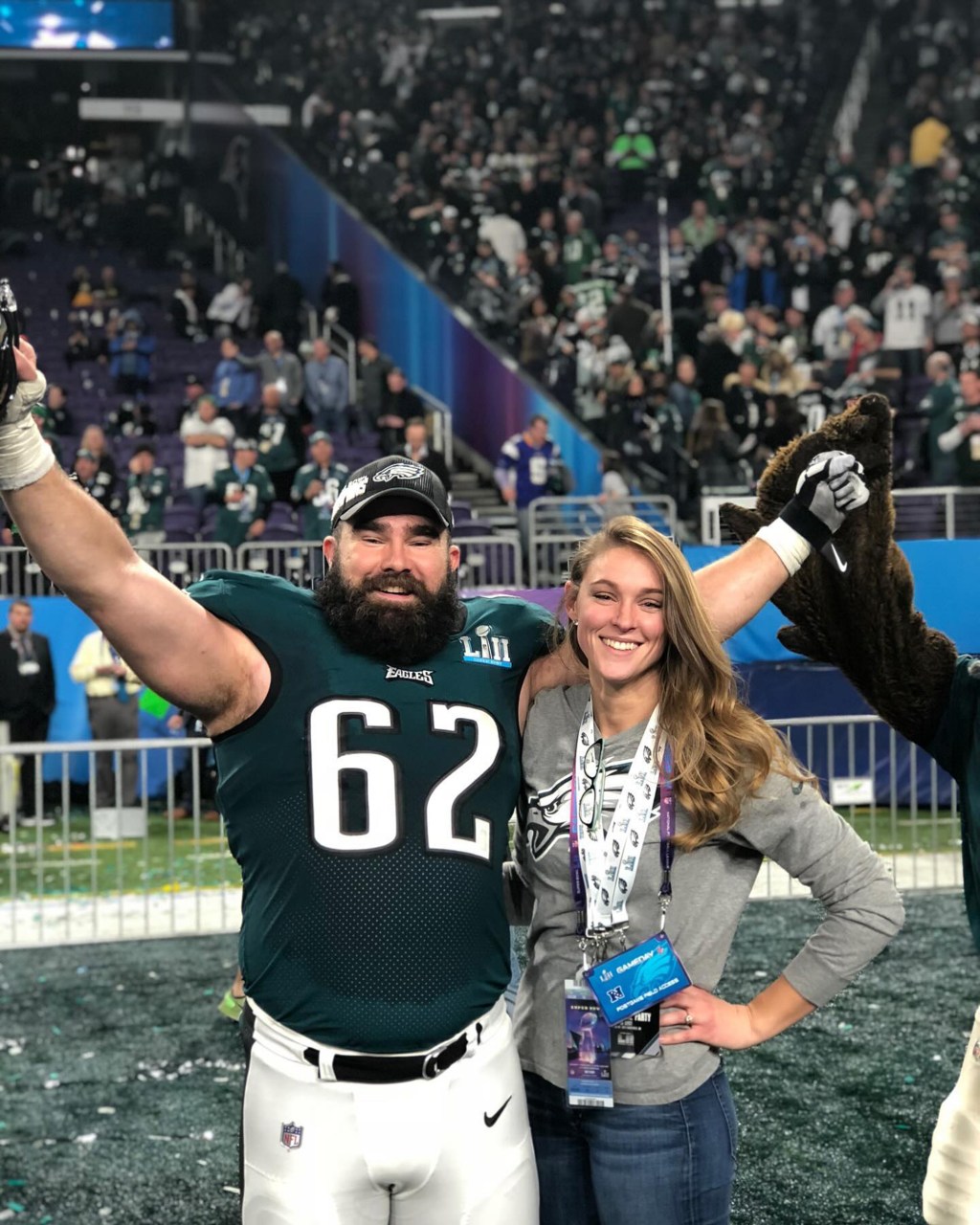 Jason Kelce in an Eagles jersey and Kylie Kelce smiling on a football field.