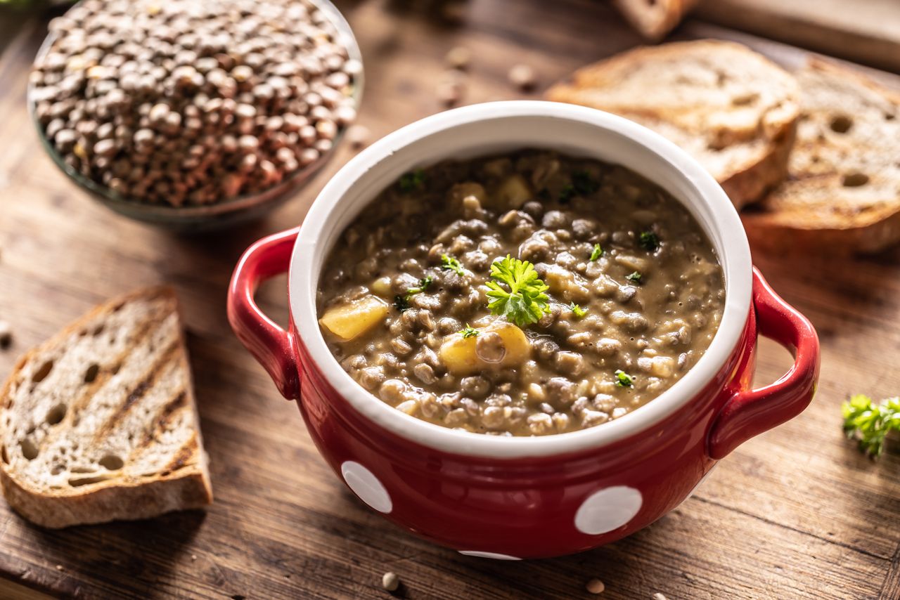A bowl of lentil stew with bread slices nearby