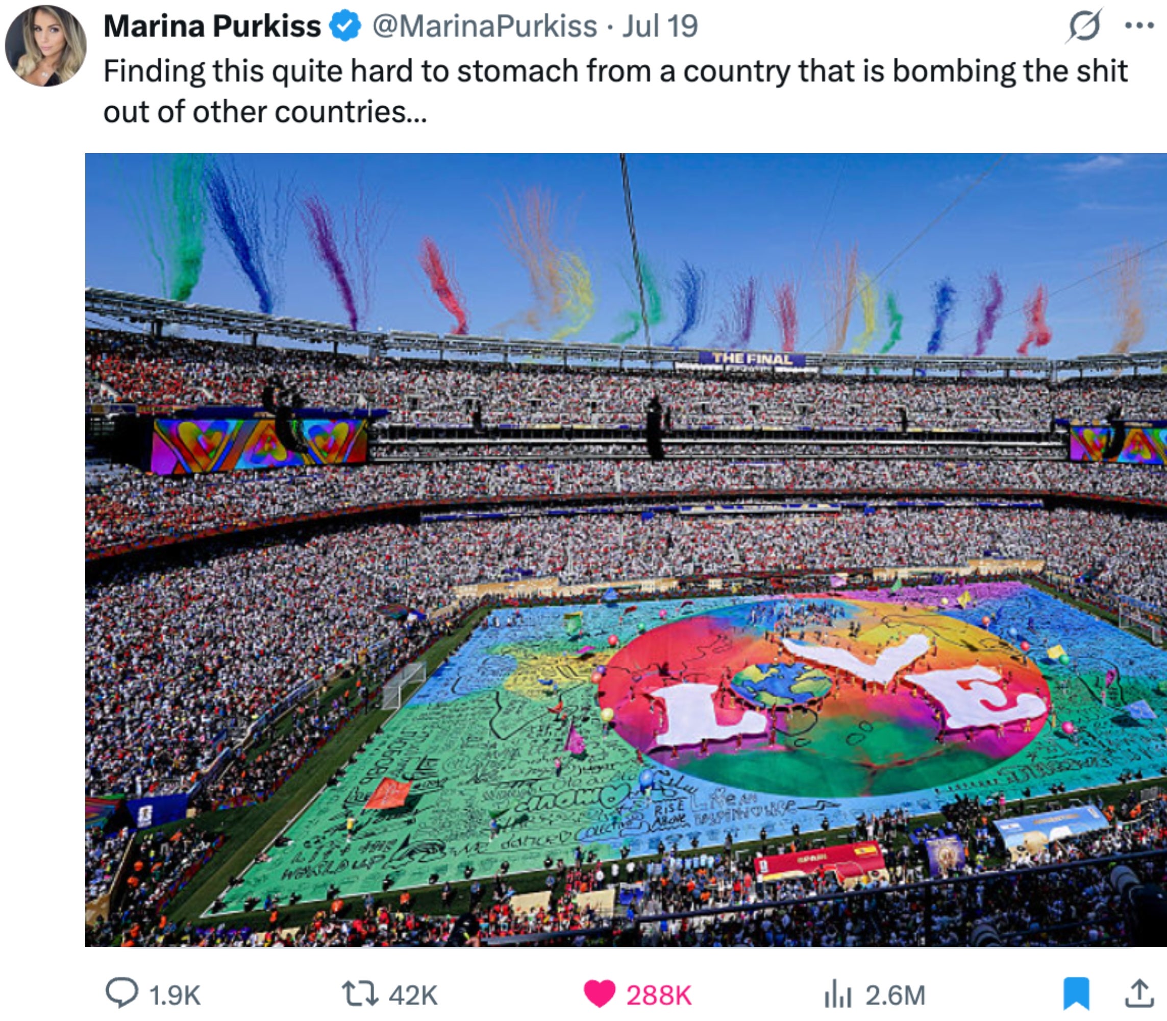 Tweet with a stadium full of people and large colorful flags on the field, discussing a country's actions