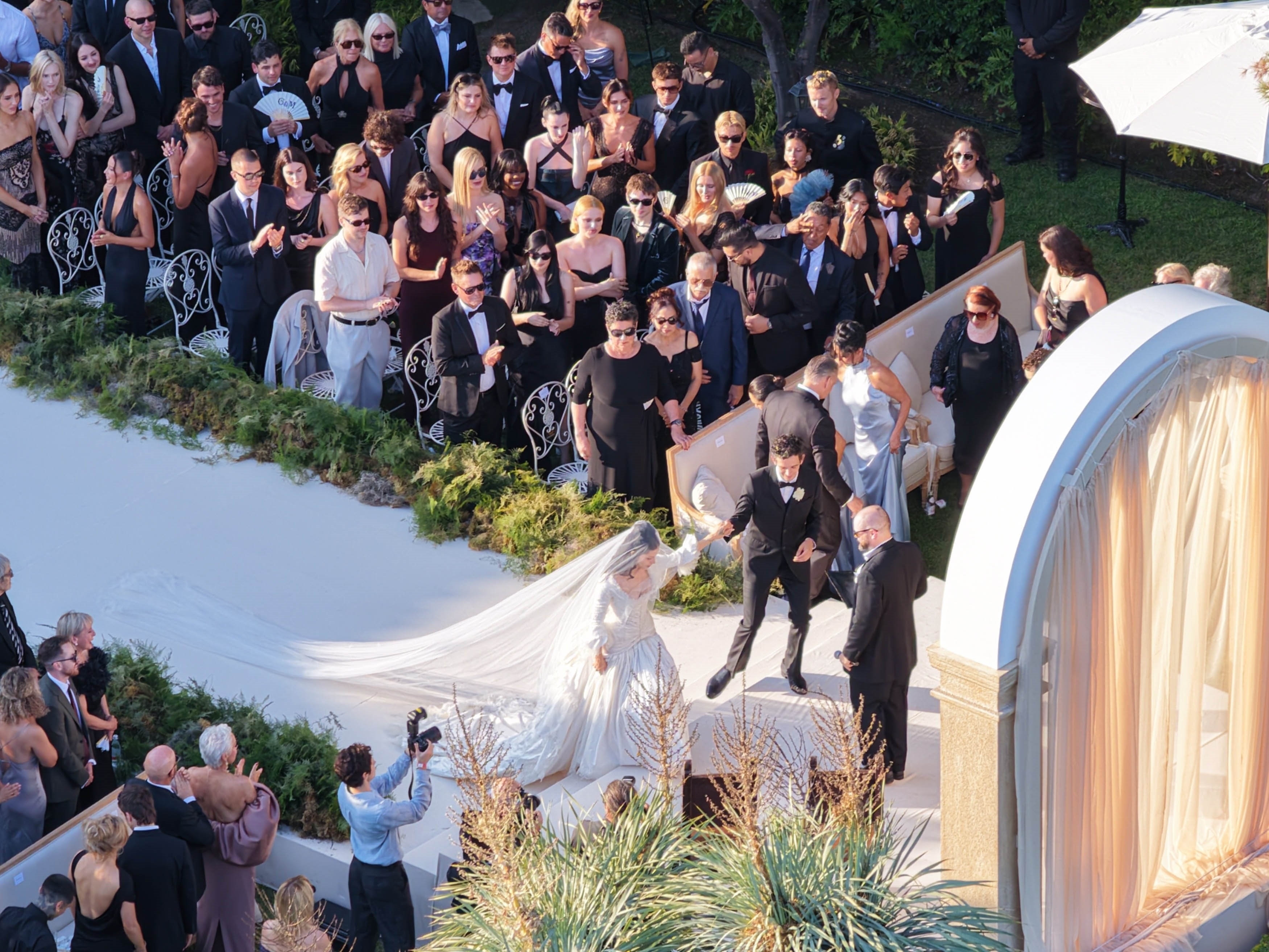Aerial view of Matty Healy and Gabbriette Bechtel at their wedding ceremony, surrounded by guests.