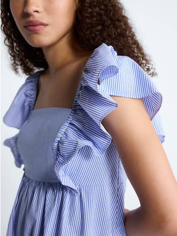 Person wearing a sleeveless dress with ruffled, striped fabric