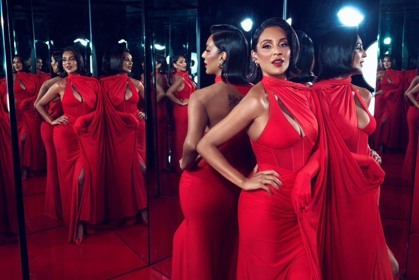 Jessel Taank wearing a red dress standing in front of a mirror.