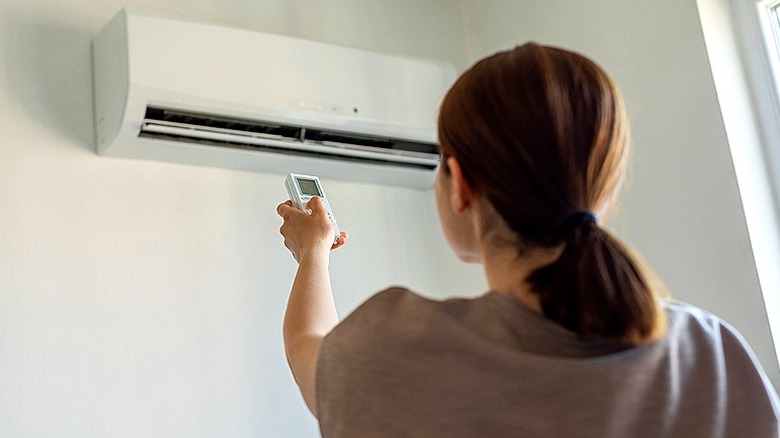 A person with their back to the camera turning on a wall AC unit