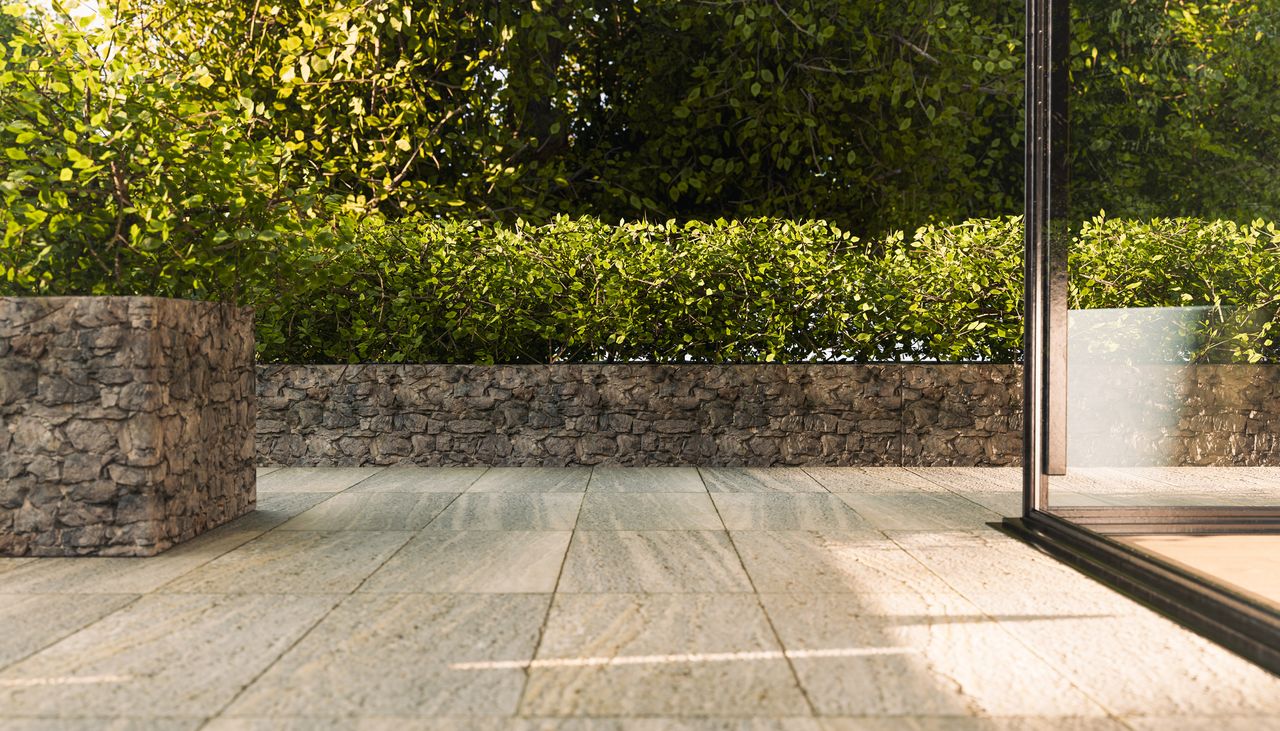 Modern patio area with stone flooring low stone walls and surrounding lush greenery