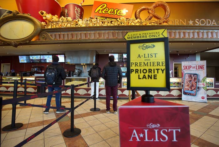 Movie theater concession stand with an A-List and Premiere Members priority lane sign, popcorn, and snack displays