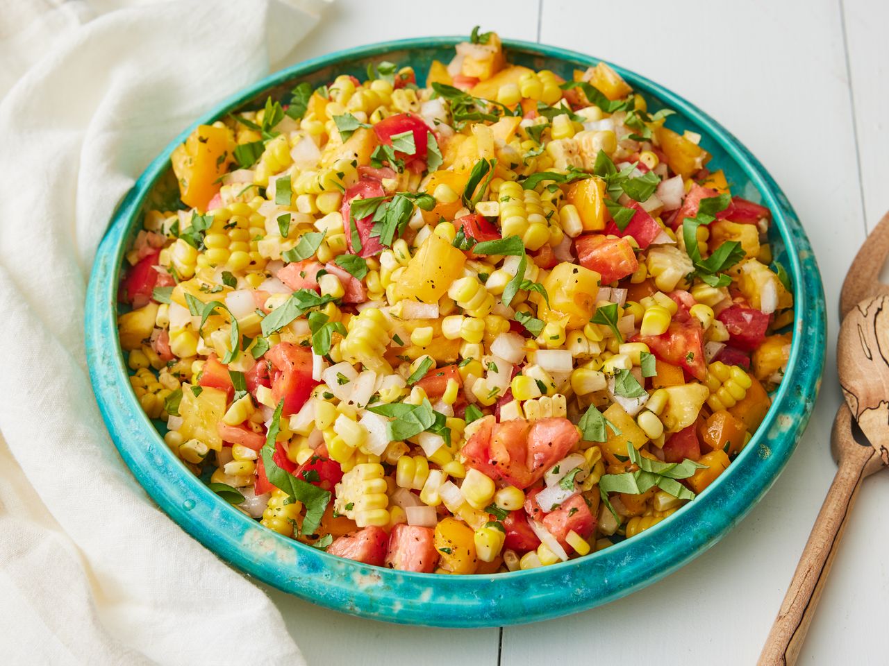 Bowl of summer corn salad with ingredients like corn, tomatoes, and herbs mixed together