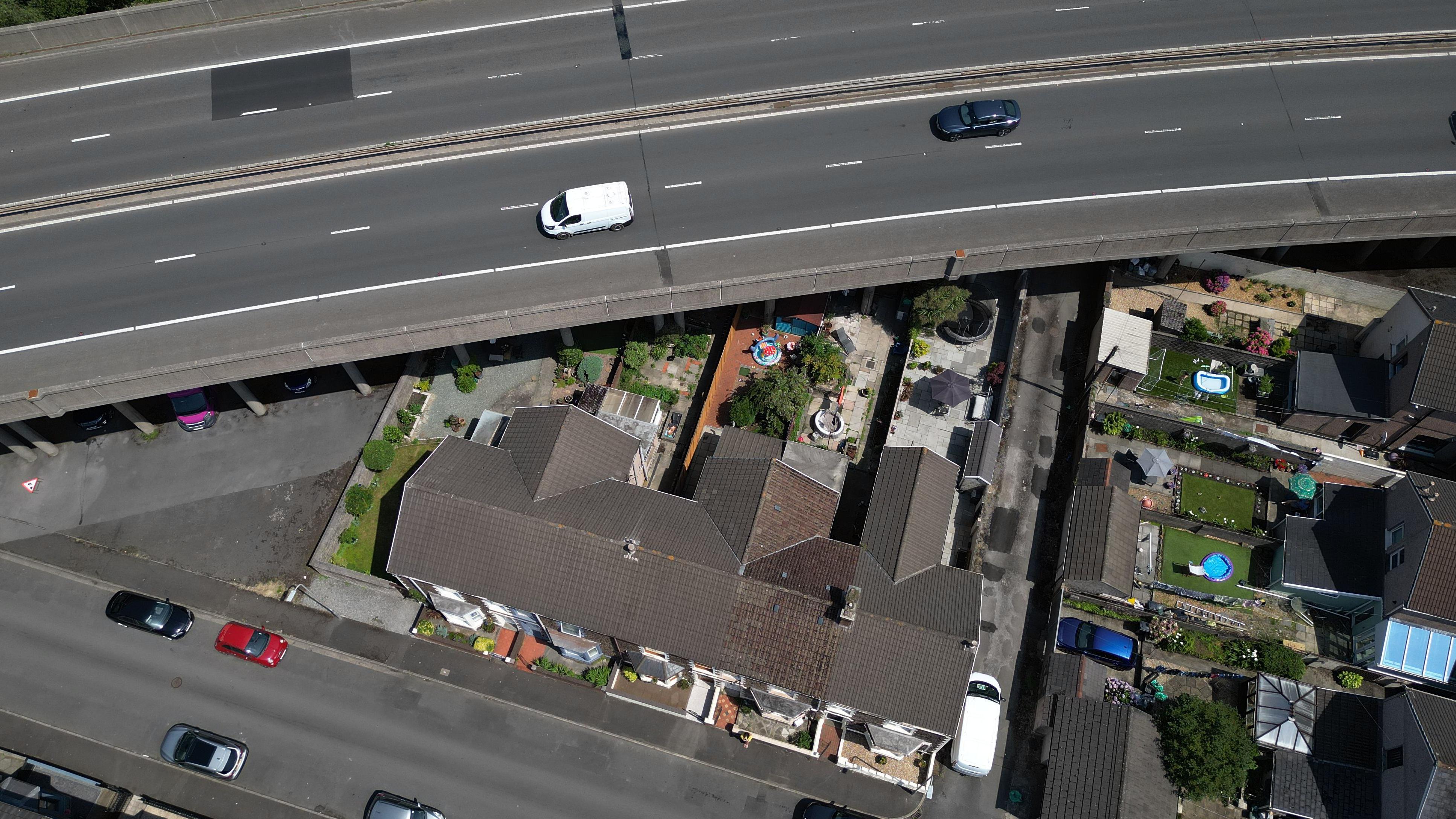 The M4 sweeps over back gardens are close to houses as it passes through the narrow space of land between hills and the sea at Port Talbot