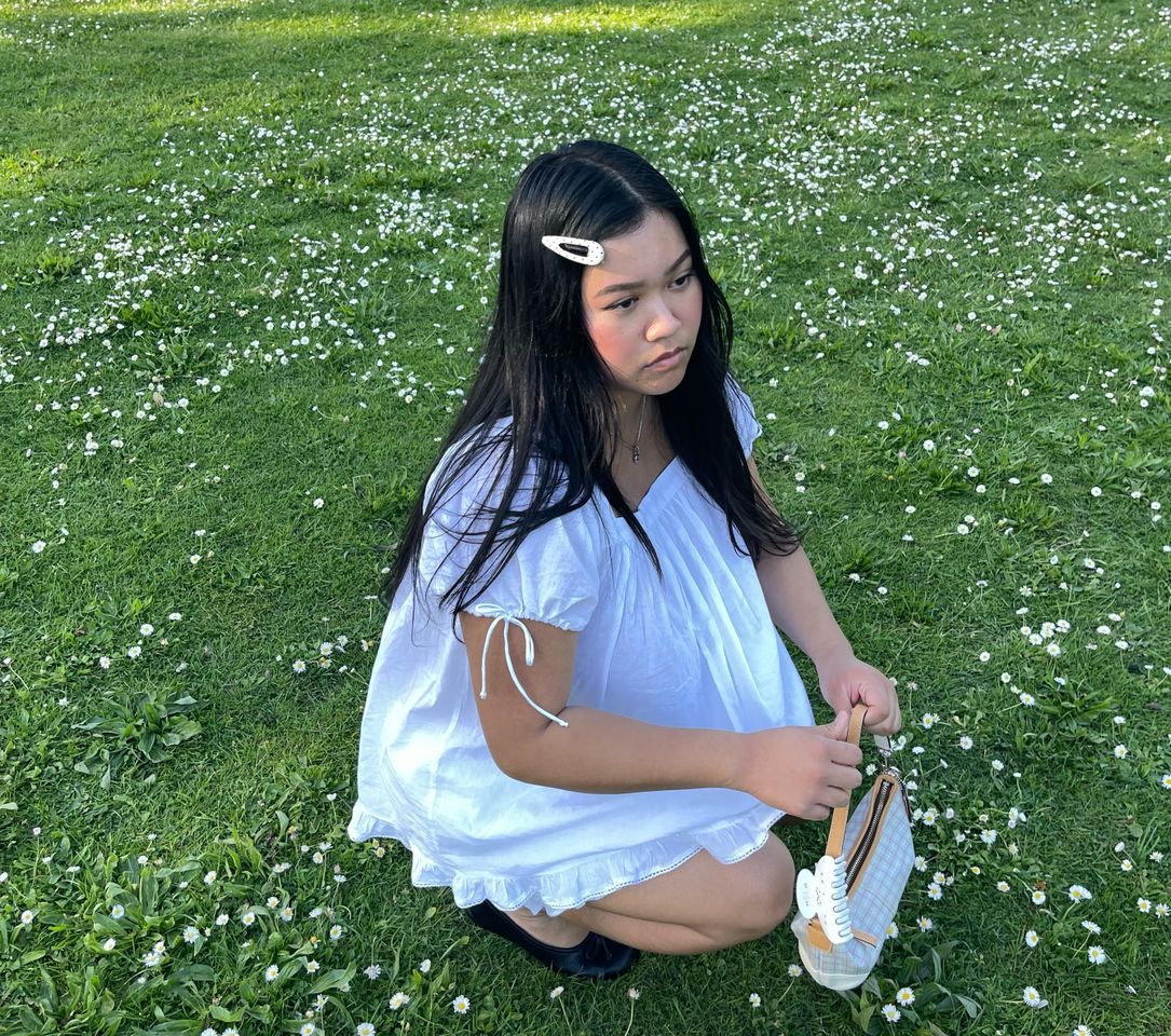 A woman squatting on grass holding a small basket