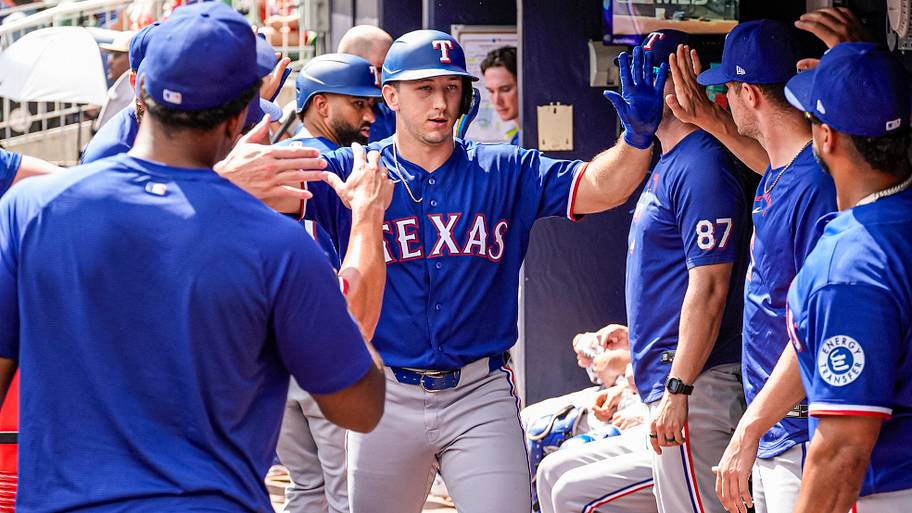 Texas Rangers left fielder Wyatt Langford celebrates with teammates in the dugout.