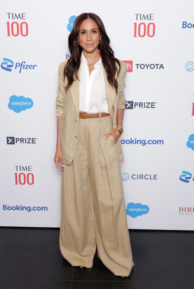 Meghan Duchess of Sussex at a TIME 100 event standing in front of a sponsor backdrop
