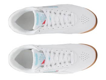 Top view of white casual sneakers with perforated toes and branded Reebok logo detailing on the tongue and side
