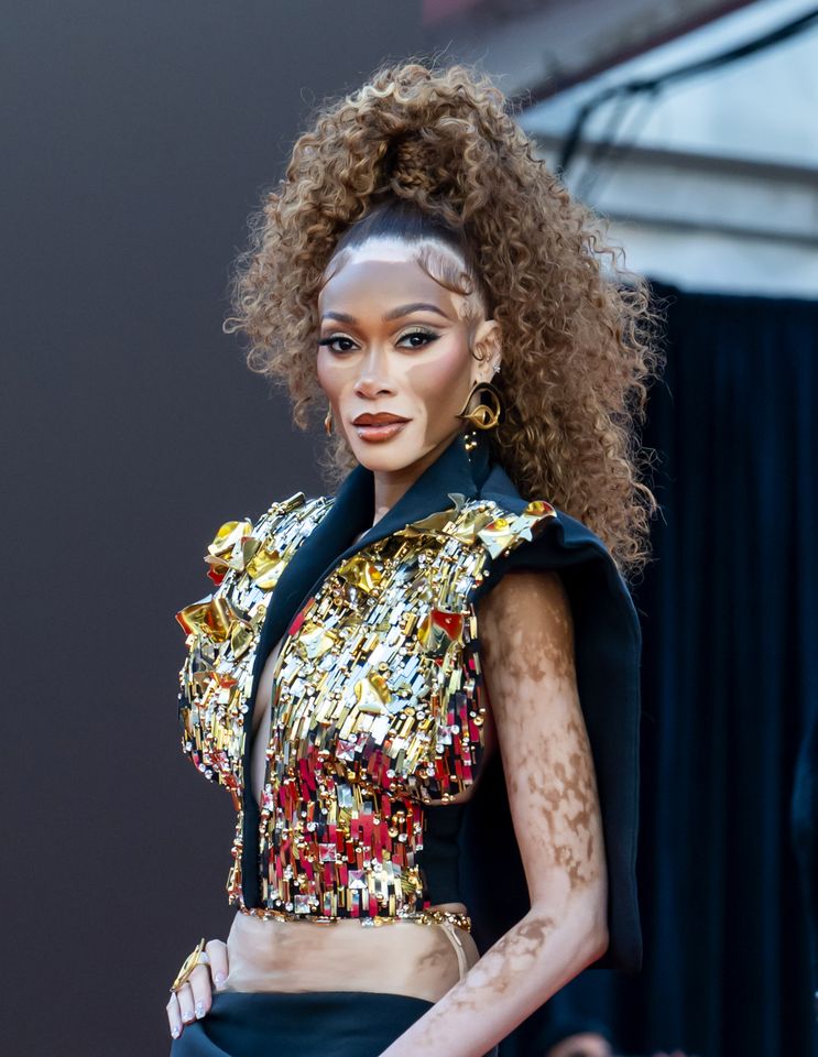 A model on a runway wearing an ornate outfit with a dramatic hairstyle