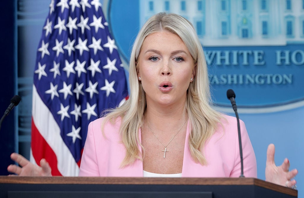 A woman at a podium speaks passionately during a press event, positioned in front of a U.S. flag and a backdrop labeled "The White House Washington."