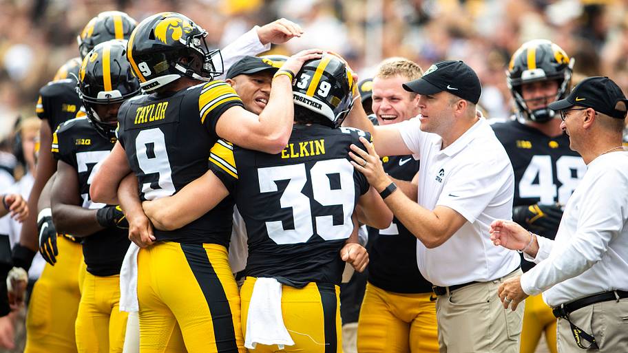 Iowa's Luke Elkin (39) is embraced by teammates Tory Taylor (9) and placekicker Aaron Blom, right.