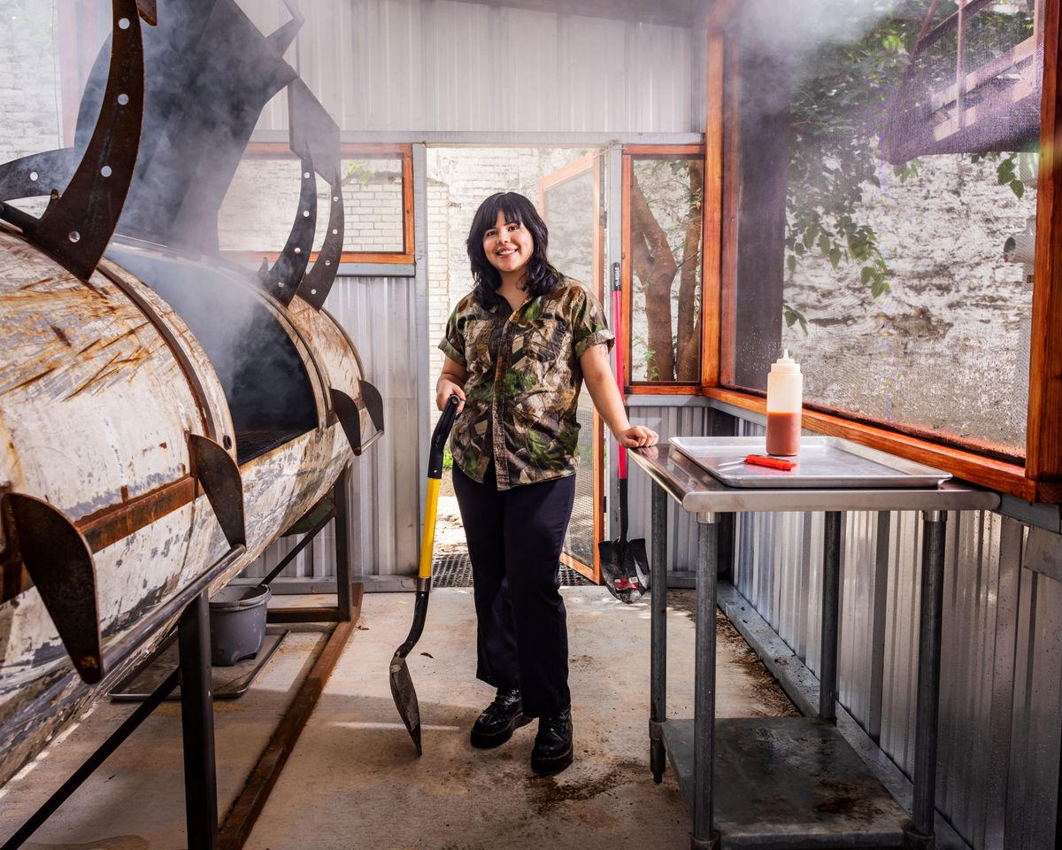 Woman standing in front of a large smoker making BBQ