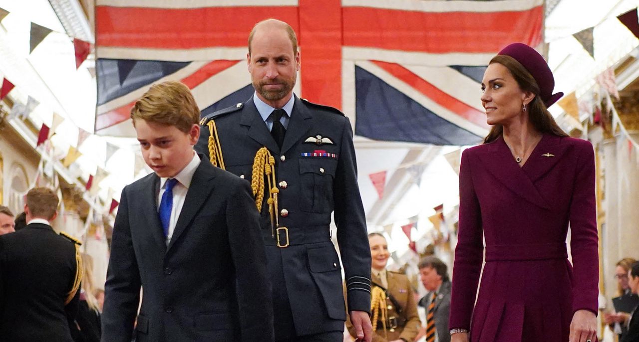 Prince George walking in front of Prince William and Prince Kate and a Union Jack flag