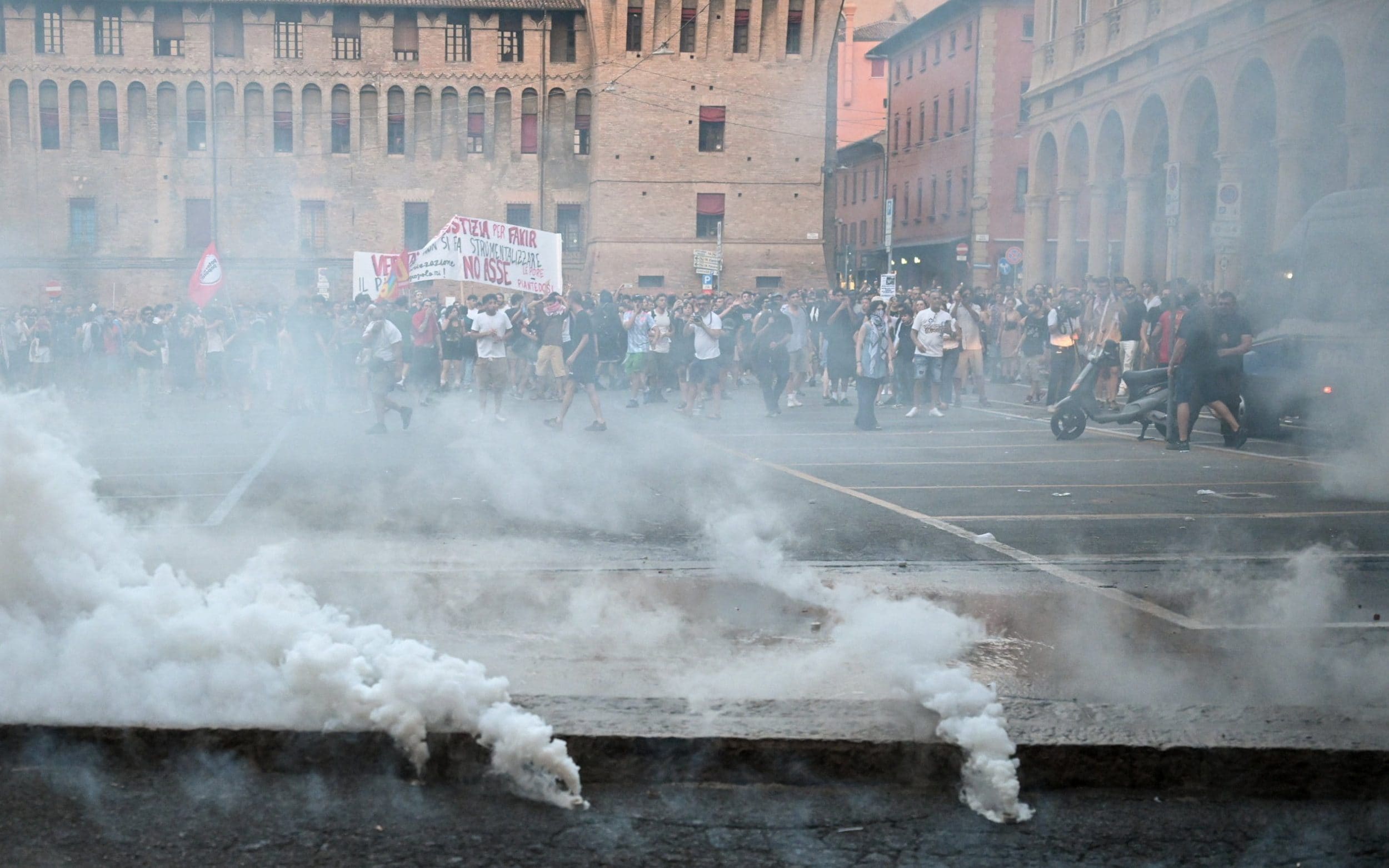 Smoke rises from canisters in front of protesters as police move to disperse a demonstration following the death of Abderrahim Fakir, in Bologna