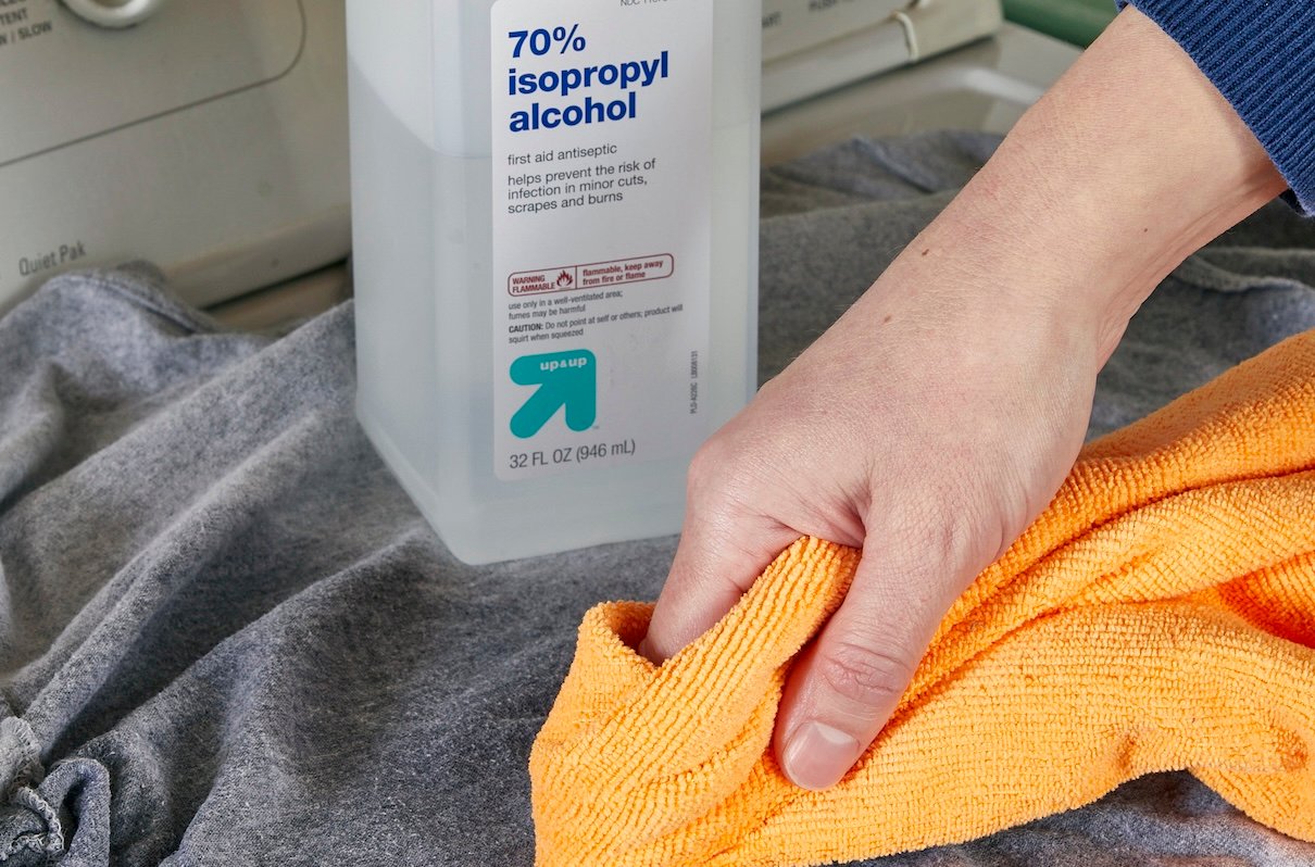Woman cleans a grey Tshirt with a microfiber cloth and rubbing alcohol.