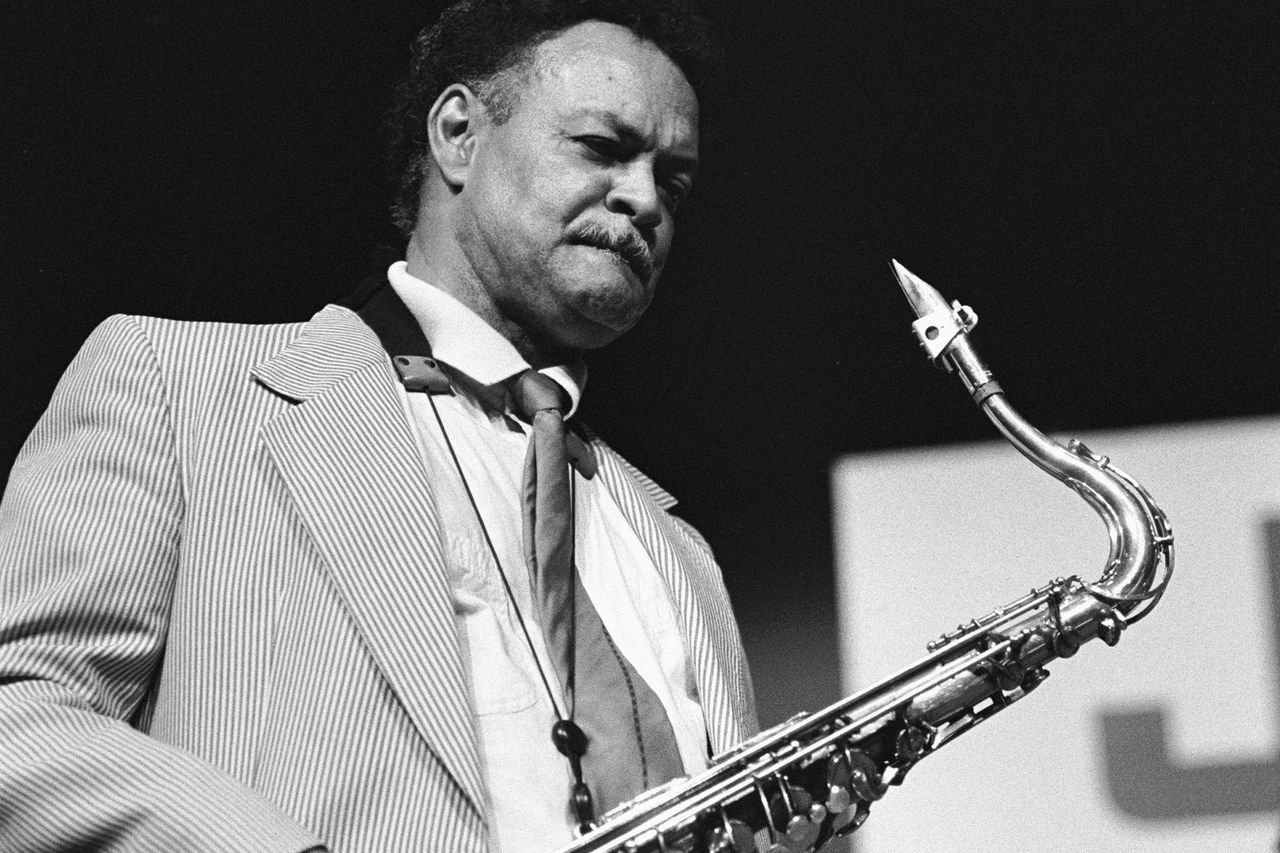 A saxophonist in a suit performing with intensity