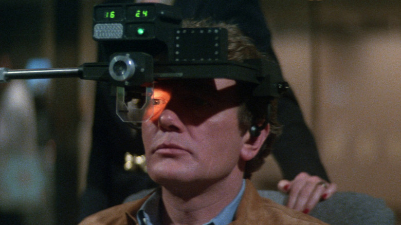 Albert Finney as Dr. Larry Roberts wearing a device on his head in Looker