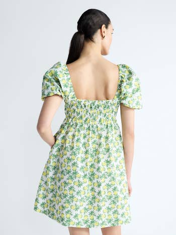 Person in a floral dress with puff sleeves and a square neck, facing away, showcasing the back design