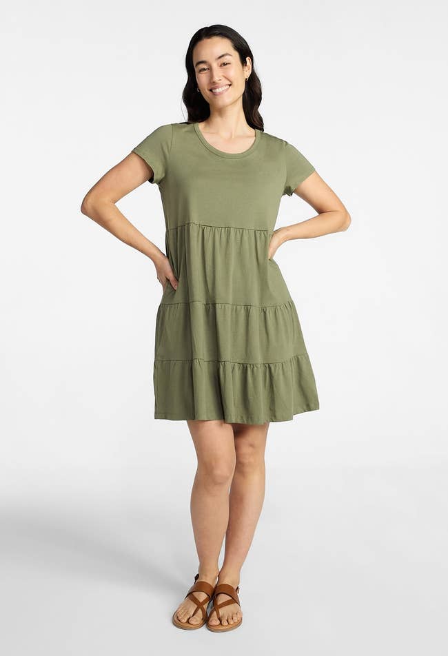 Person wearing a tiered casual dress and sandals, standing confidently with hands on hips. Perfect for a relaxed, stylish look