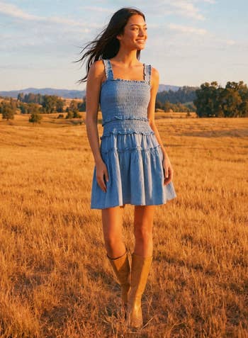 Model in a casual sundress and boots walking in a golden field, smiling into the distance