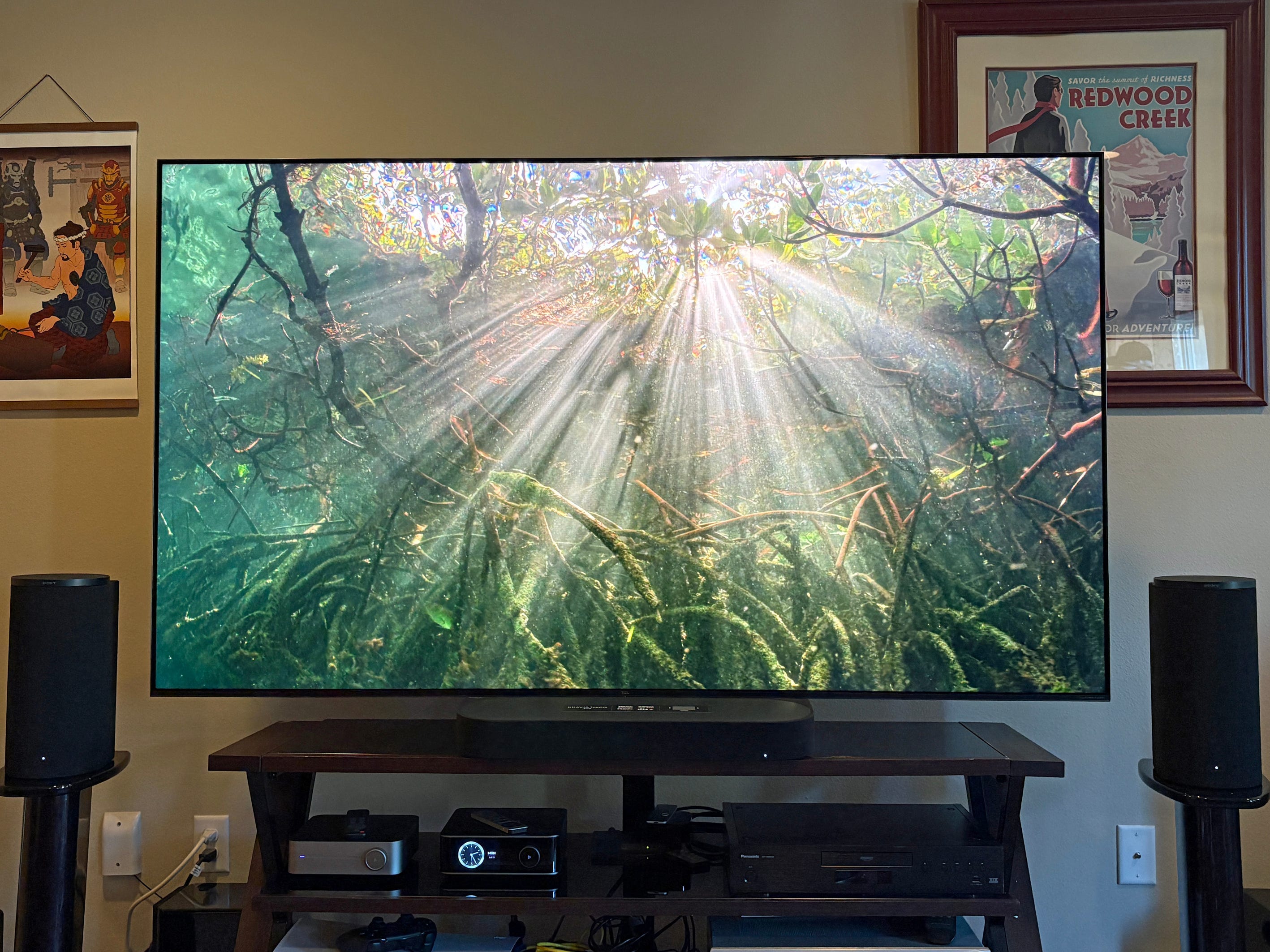 A TCL QM7L TV displays sunbeams underwater while set ip above home theater components and speakers in our reviewer's living room.