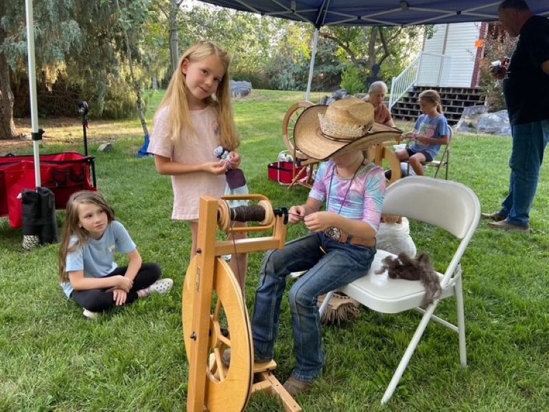 Children try their hand at spinning raw wool into yarn during a previous Pioneer Day celebration at the Snake River Homestead near Shelley. | Courtesy photo