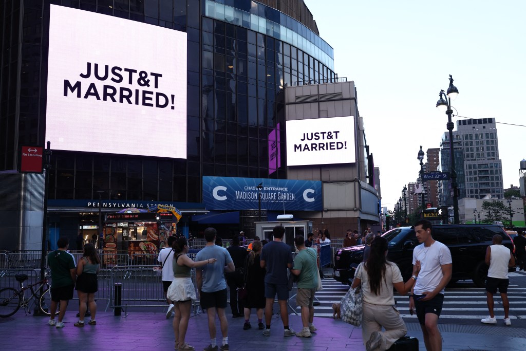People gather in front of Madison Square Garden with signs reading