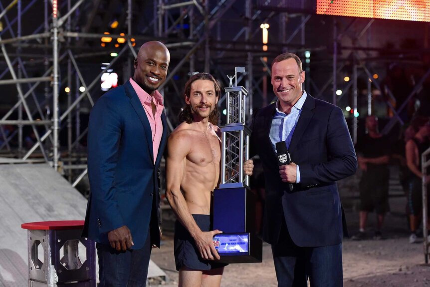 Akbar Gbajabiamila, Isaac Caldiero, and Matt Iseman smiling on American Ninja Warrior Season 7.