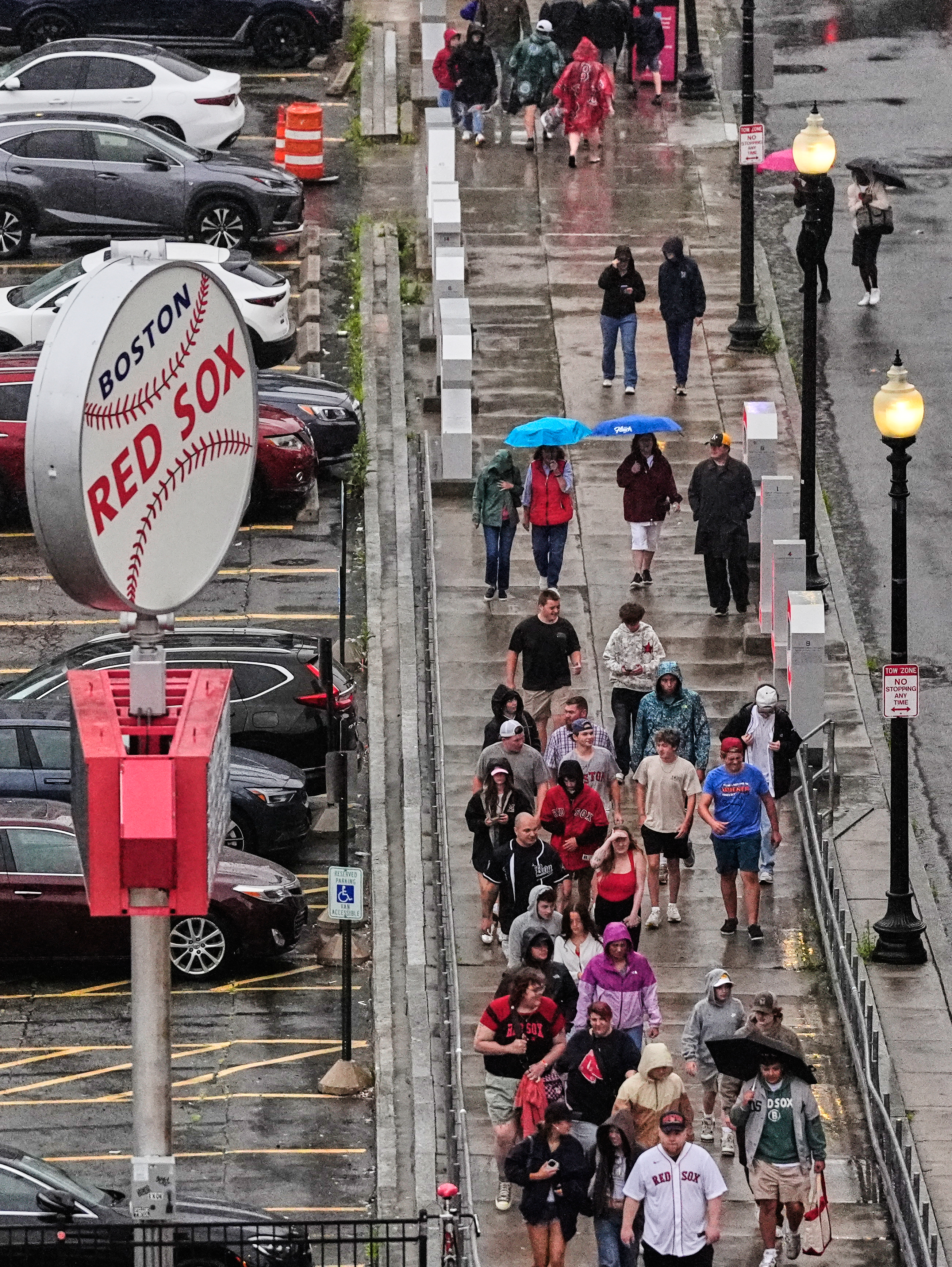 Fans walk towards Fenway Park as a baseball game between the Boston Red Sox and Baltimore Orioles was postponed due to heavy rain, Tuesday, July 21, 2026, in Boston. (AP Photo/Charles Krupa)
