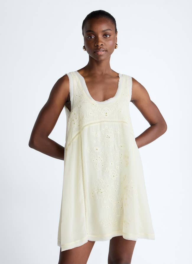 Person wearing a sleeveless, embroidered, knee-length dress with a scoop neckline, suitable for a summer outing or casual event