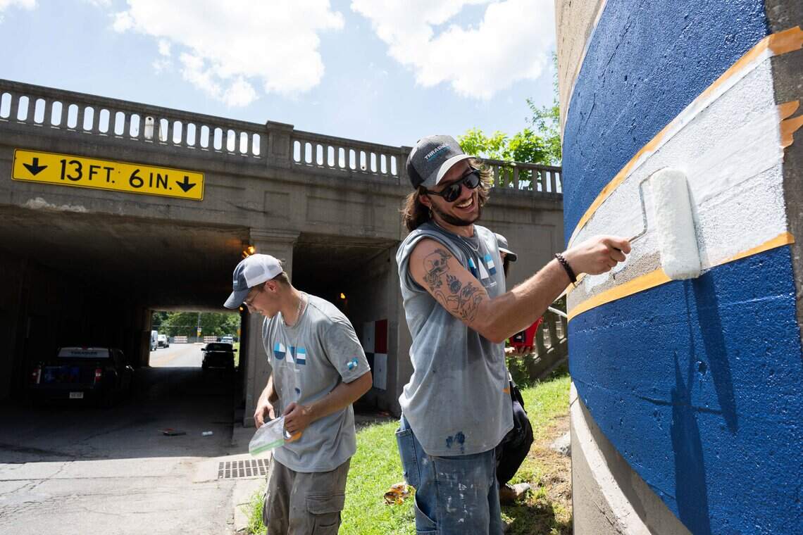 Joe Reckamp paints a flag on the wall as part of a series of flag murals on Van Brunt Boulevard in Kansas City, on Monday, July 20, 2026. When complete, the mural will feature more than 100 flags representing the demographics of the neighborhood.