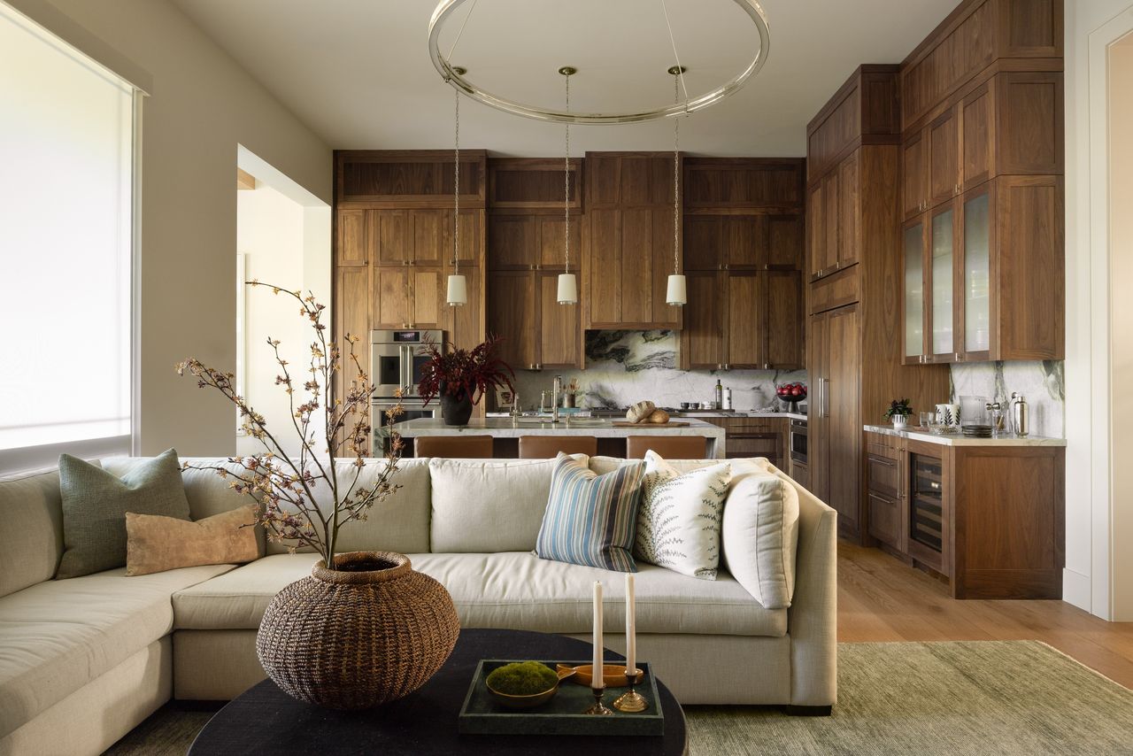 A modern kitchen with wooden cabinets and a seating area with a decorative vase and cushions in the foreground