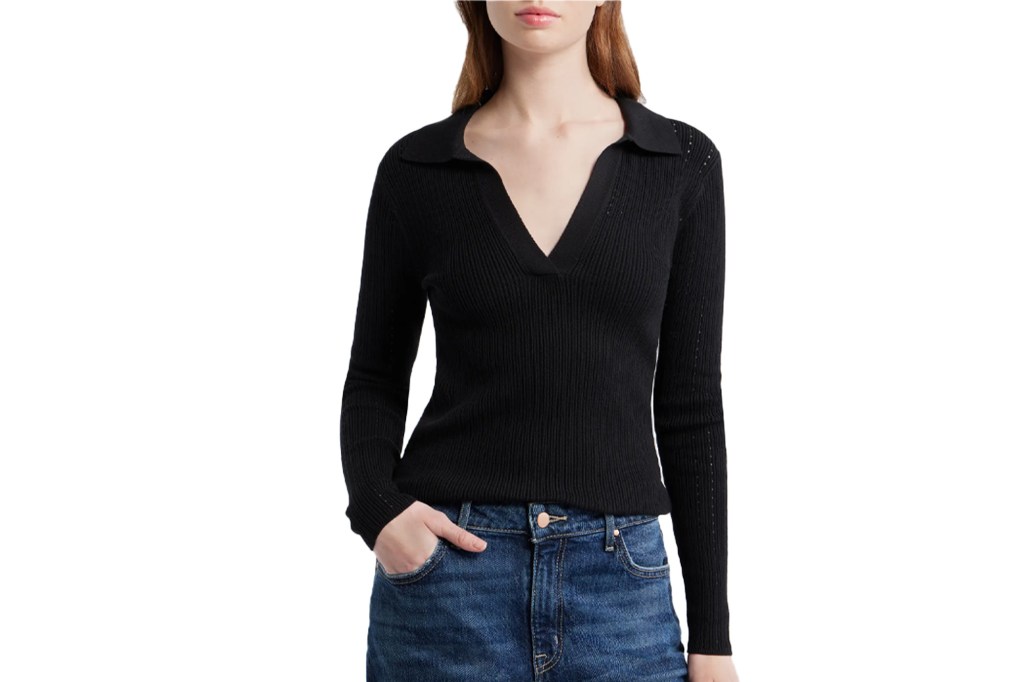 Woman wearing a black ribbed long-sleeve V-neck top and blue jeans.