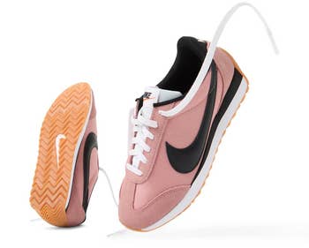 Two pink sneakers with a swoosh logo, showcasing a herringbone patterned sole and white laces, ideal for casual or athletic wear