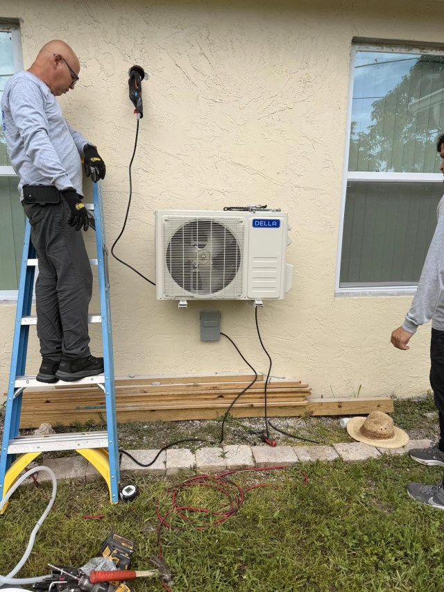 Two men installing a heat pump.