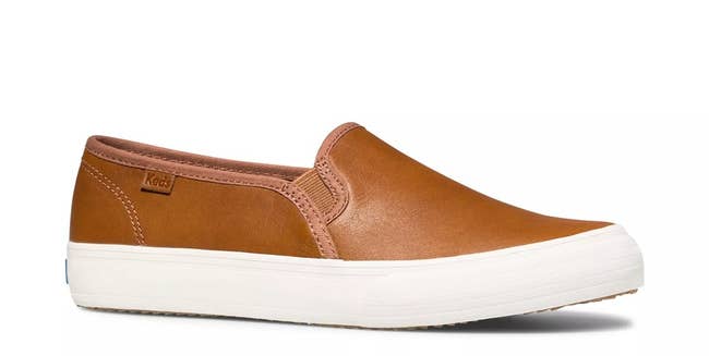 A brown leather slip-on sneaker with a white sole, suitable for casual wear