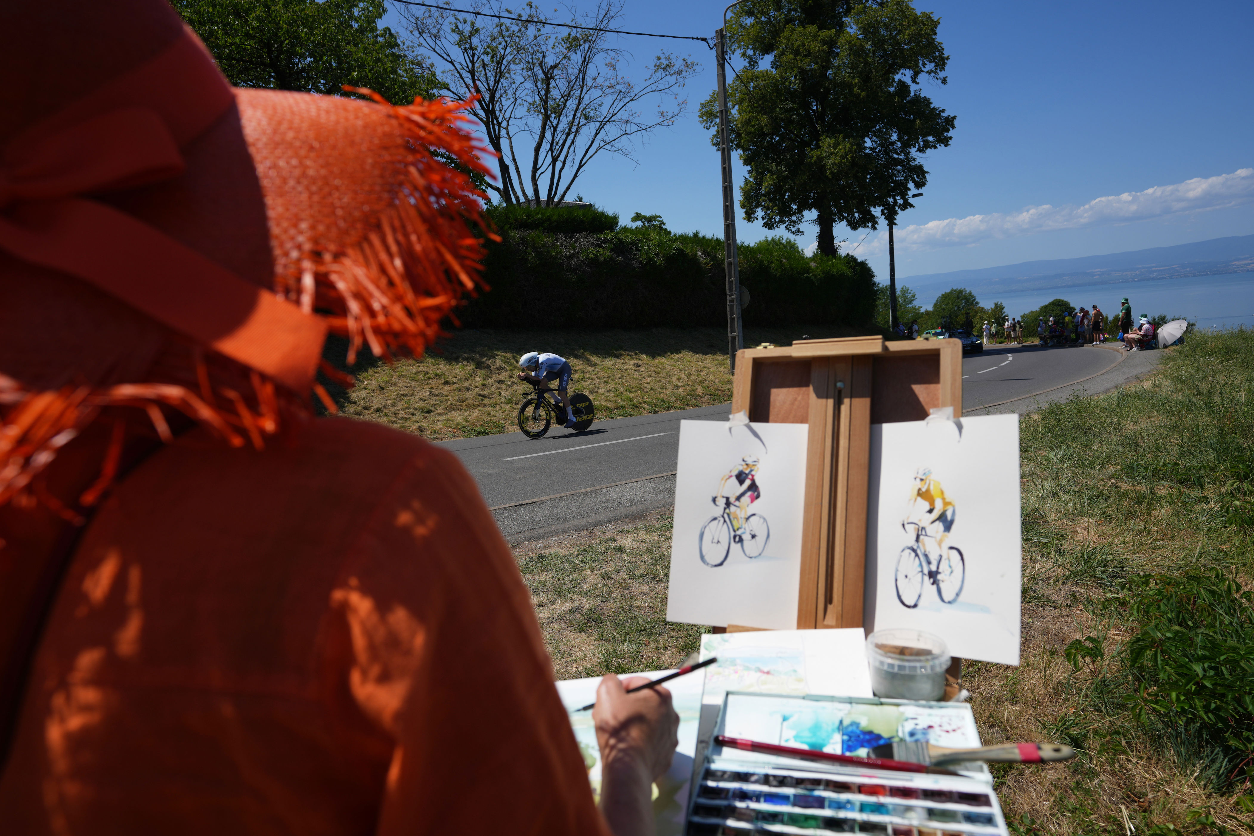 A woman draws as Britain's Fred Wright rides during the sixteenth stage of the Tour de France cycling race, an indivdual time-trial with start in Evian-Les-Bains and finish in Thonon-les-Bains, France, Tuesday, July 21, 2026. (AP Photo/Thibault Camus)