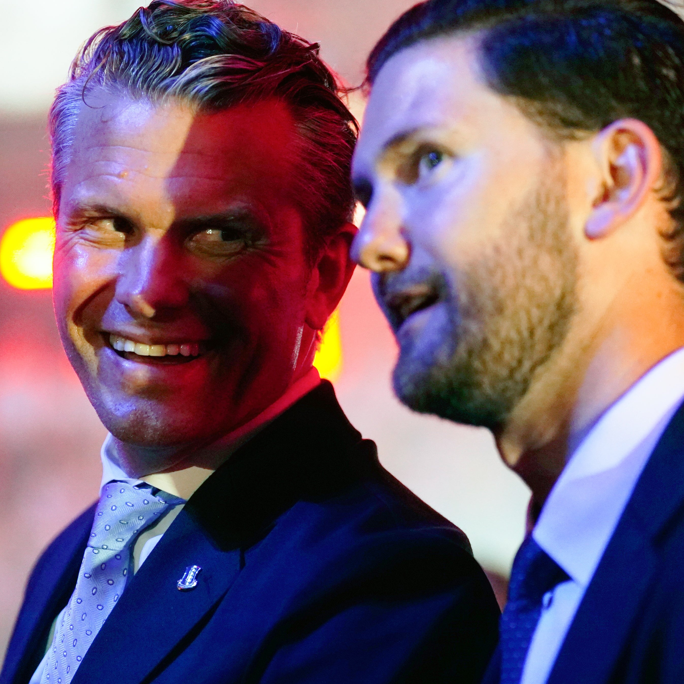 Two men in suits engaged in a conversation at a formal event